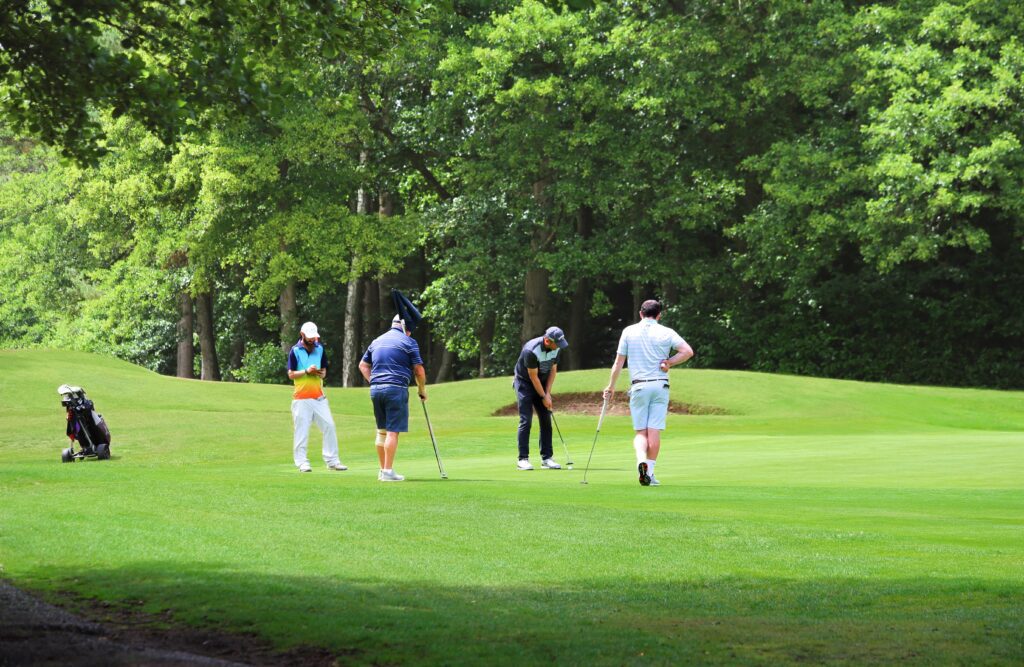 Four golfers around the pin putting