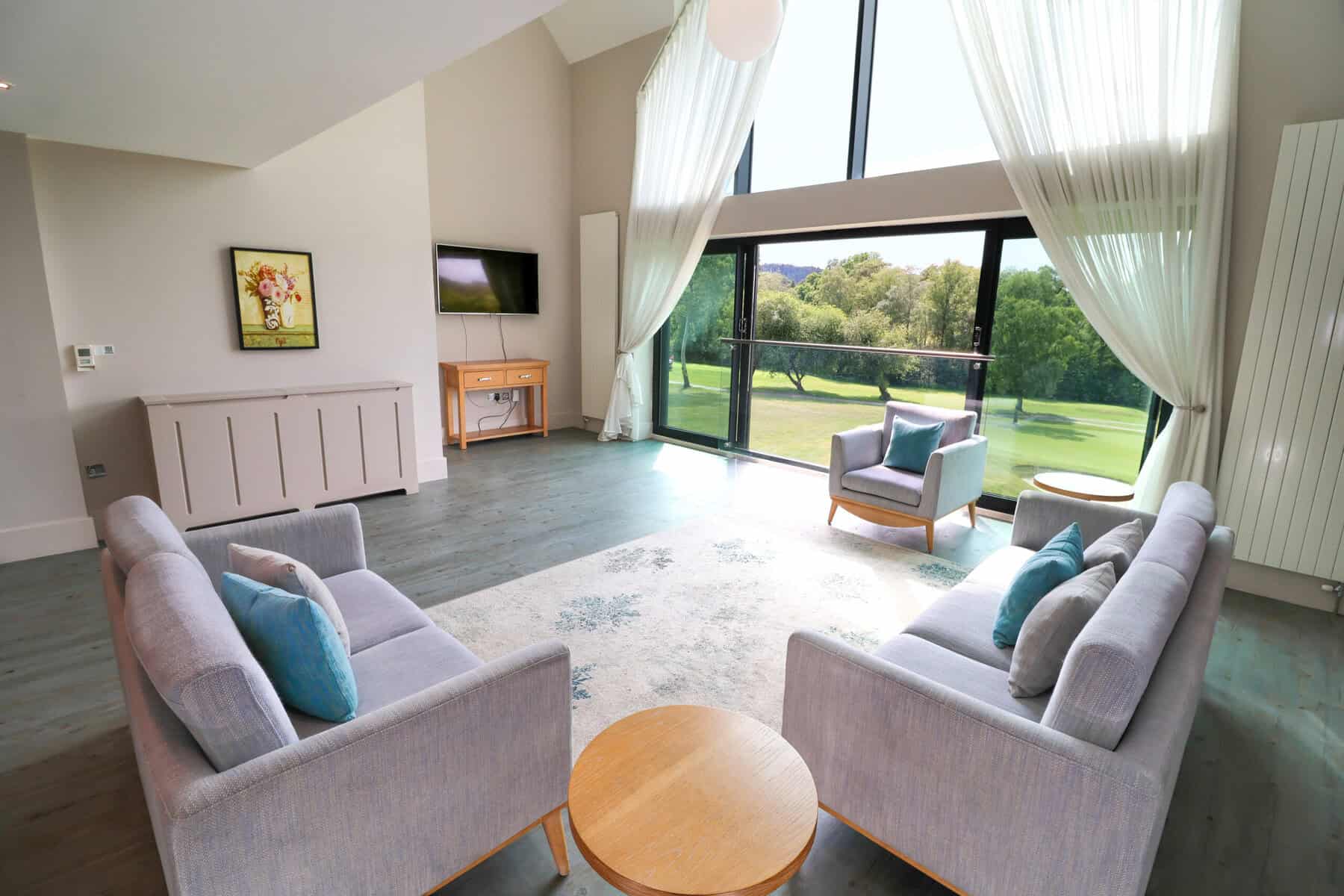 Cozy Lounge with Large Windows and Scenic Views Bright lounge with large windows overlooking lush green golf course scenery.